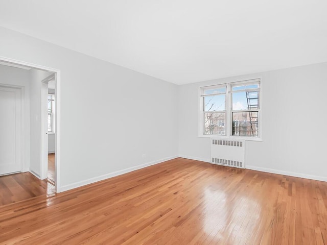 spare room featuring radiator and light hardwood / wood-style floors