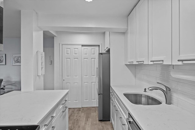 kitchen featuring appliances with stainless steel finishes, tasteful backsplash, light stone counters, sink, and white cabinets