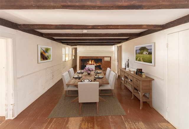 dining room featuring beam ceiling, a brick fireplace, and dark wood-type flooring