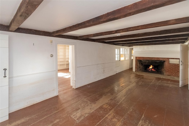 unfurnished living room with beamed ceiling, dark hardwood / wood-style flooring, and a brick fireplace