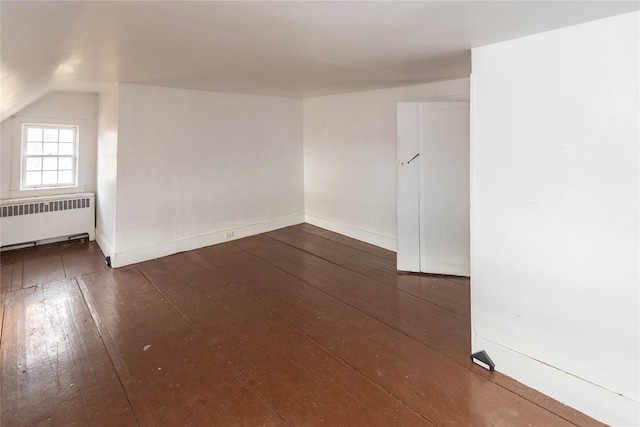 spare room with lofted ceiling, radiator heating unit, and dark wood-type flooring