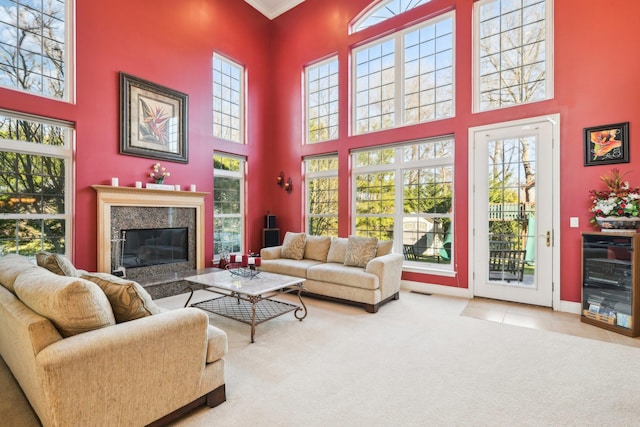 living room with plenty of natural light, ornamental molding, a high ceiling, and a premium fireplace