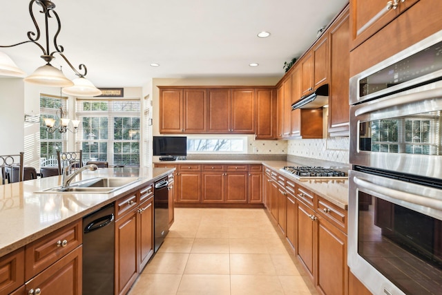 kitchen featuring light stone countertops, sink, a notable chandelier, pendant lighting, and appliances with stainless steel finishes