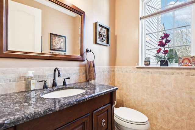 bathroom with vanity, tile walls, and toilet