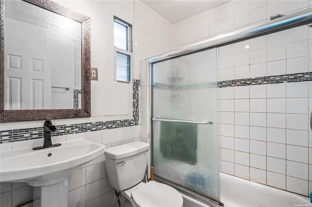 full bathroom with backsplash, bath / shower combo with glass door, sink, tile walls, and toilet