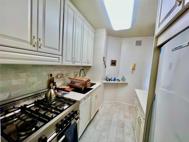 kitchen featuring white cabinets, gas stove, light stone counters, and backsplash