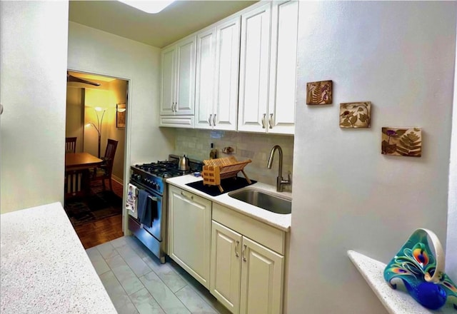 kitchen with backsplash, stainless steel gas range oven, sink, white cabinets, and light parquet flooring