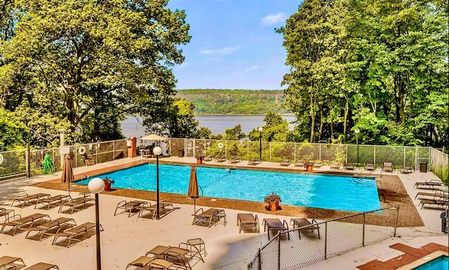 view of swimming pool featuring a patio and a water view