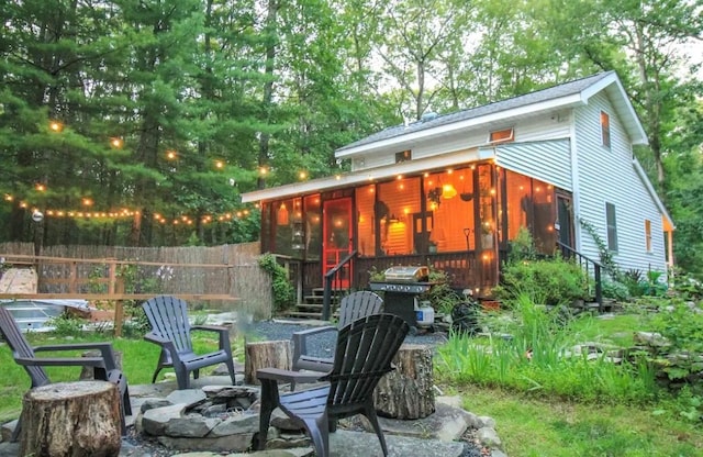 view of patio / terrace featuring a grill, a sunroom, and a fire pit