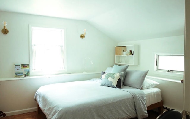 bedroom featuring a baseboard heating unit, multiple windows, and lofted ceiling