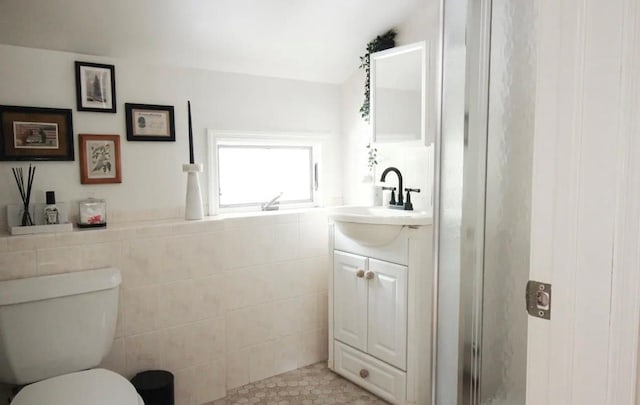 bathroom featuring vanity, toilet, and tile walls