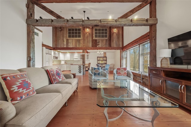 living room featuring hardwood / wood-style flooring, beam ceiling, wood walls, and a towering ceiling