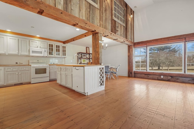 kitchen with white appliances, white cabinets, an inviting chandelier, decorative backsplash, and plenty of natural light