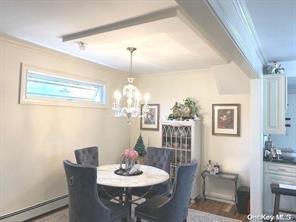 dining area with ornamental molding, a notable chandelier, and baseboard heating