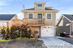 view of front of property featuring a garage, concrete driveway, and stairway