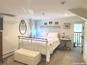 bedroom with a baseboard radiator, a wall mounted AC, and dark colored carpet