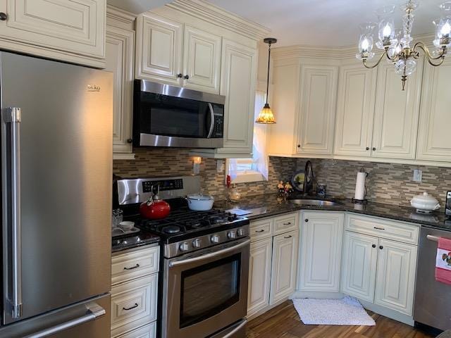 kitchen featuring tasteful backsplash, dark wood-style flooring, a sink, stainless steel appliances, and a notable chandelier