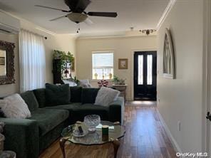 living room featuring a ceiling fan, baseboards, ornamental molding, and wood finished floors