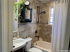 full bathroom featuring toilet, shower / bath combo with shower curtain, tile walls, and vanity