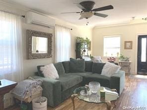 living room with ceiling fan, wood finished floors, and a wall mounted air conditioner