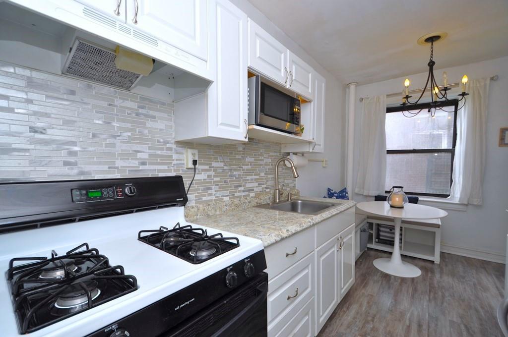 kitchen with gas range, sink, a chandelier, decorative light fixtures, and white cabinets