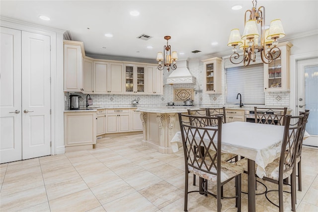 kitchen featuring custom exhaust hood, a kitchen island, decorative light fixtures, and cream cabinets