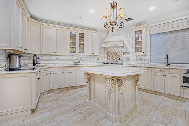 kitchen with cream cabinets, a center island, decorative light fixtures, and tasteful backsplash