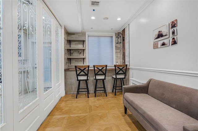 dining space with indoor bar, crown molding, and light parquet flooring