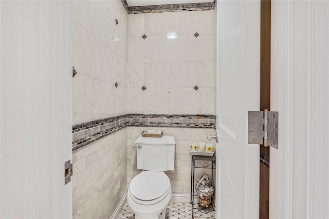 bathroom with toilet and tile walls