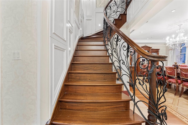 stairway featuring parquet floors, ornamental molding, and a notable chandelier