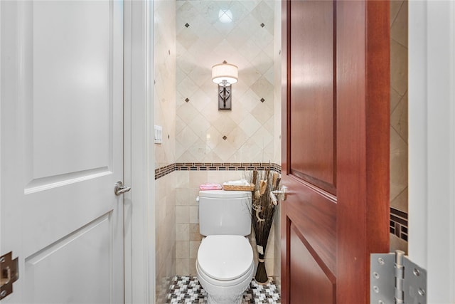 bathroom featuring toilet and tile walls