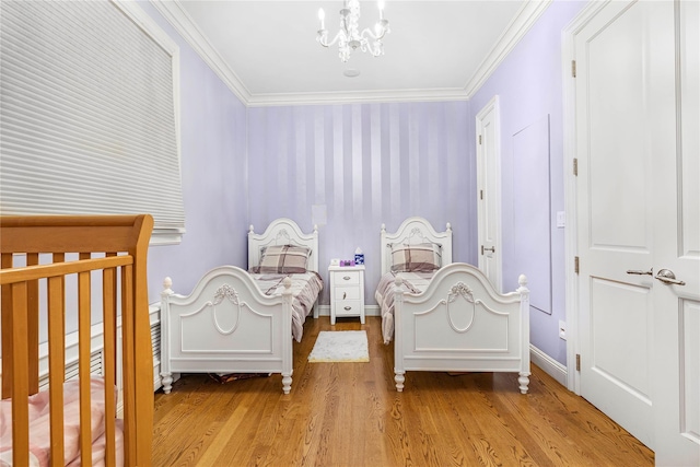 unfurnished bedroom with an inviting chandelier, ornamental molding, light hardwood / wood-style flooring, and a nursery area