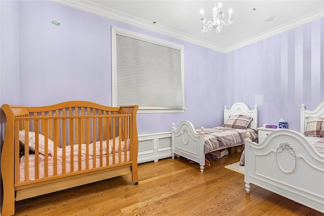 bedroom featuring light hardwood / wood-style flooring, ornamental molding, and a notable chandelier