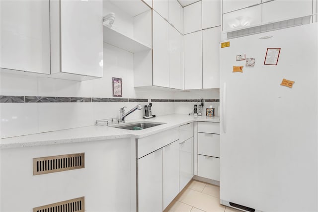 kitchen featuring white cabinetry, white refrigerator, backsplash, light tile patterned floors, and tile walls