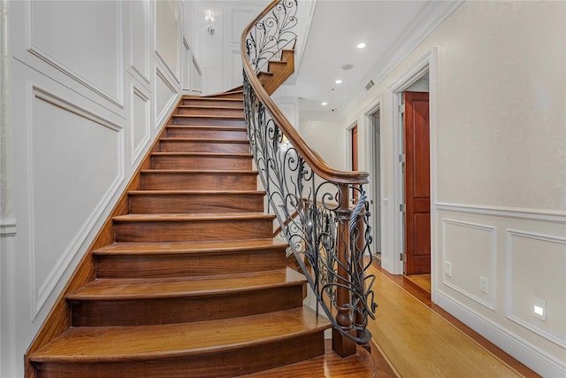 stairs featuring ornamental molding and hardwood / wood-style flooring