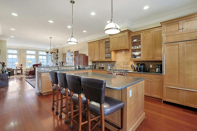 kitchen featuring kitchen peninsula, a kitchen breakfast bar, backsplash, paneled fridge, and hanging light fixtures