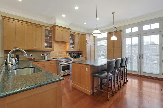 kitchen featuring high quality appliances, french doors, sink, decorative backsplash, and a kitchen island