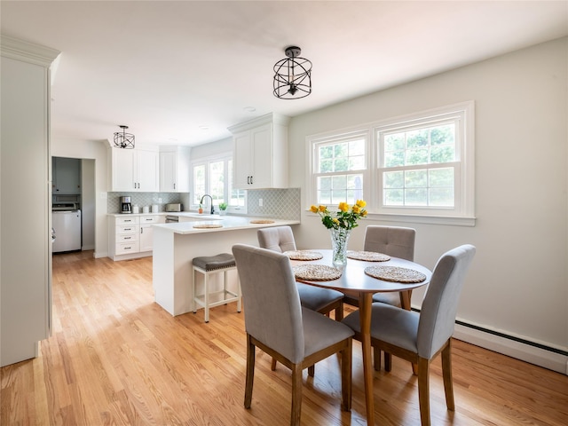 dining space with light hardwood / wood-style floors, washer / clothes dryer, and sink