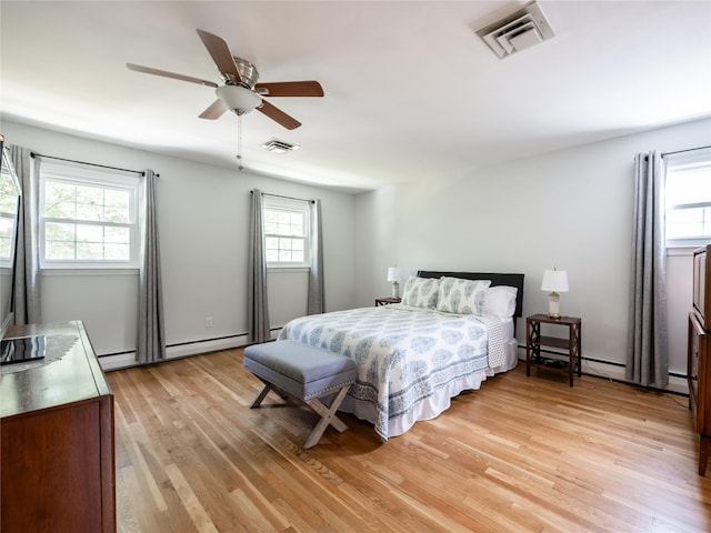 bedroom with ceiling fan, a baseboard heating unit, and light wood-type flooring