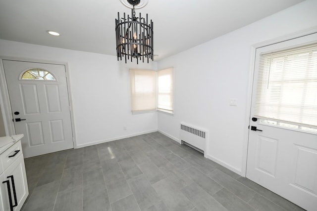 foyer entrance featuring a wealth of natural light, radiator heating unit, and a notable chandelier