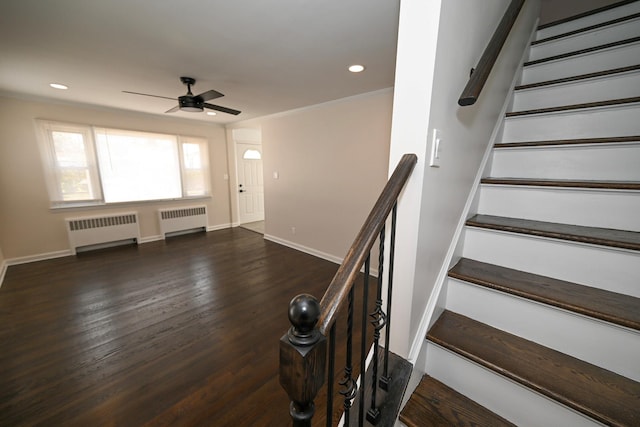 stairs with radiator heating unit, ceiling fan, ornamental molding, and wood-type flooring