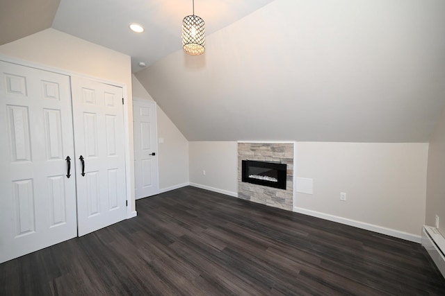 additional living space with a fireplace, baseboard heating, dark wood-type flooring, and vaulted ceiling