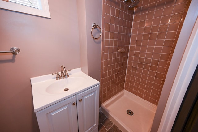 bathroom featuring a tile shower, tile patterned flooring, and vanity