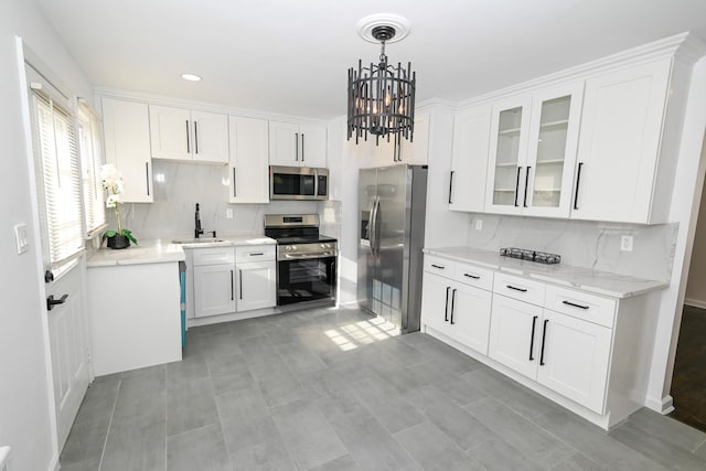 kitchen with light stone countertops, stainless steel appliances, sink, pendant lighting, and white cabinetry