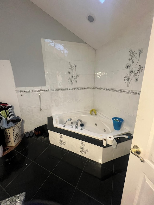 bathroom with tile patterned flooring, tiled bath, vaulted ceiling, and tile walls