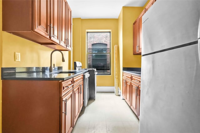 kitchen featuring stainless steel refrigerator, sink, and dark stone countertops