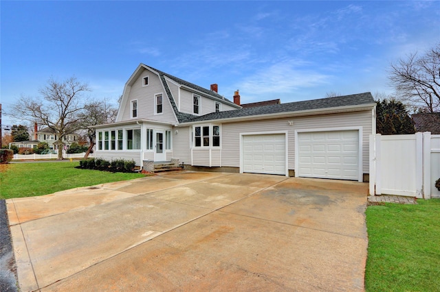 view of front of home featuring a front yard, a garage, and a sunroom