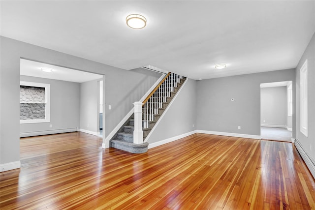 unfurnished living room featuring hardwood / wood-style floors and baseboard heating