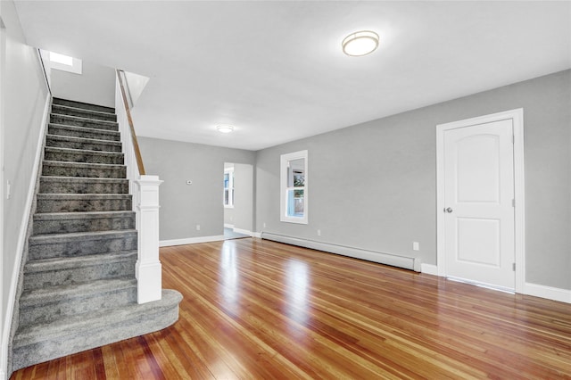 unfurnished living room with baseboard heating and light wood-type flooring