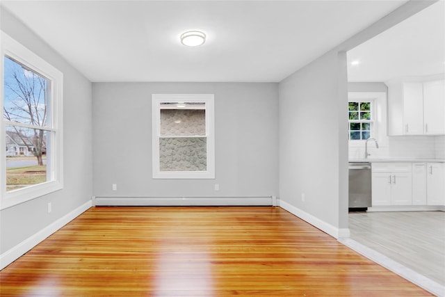 unfurnished dining area with sink, light hardwood / wood-style flooring, and a baseboard radiator